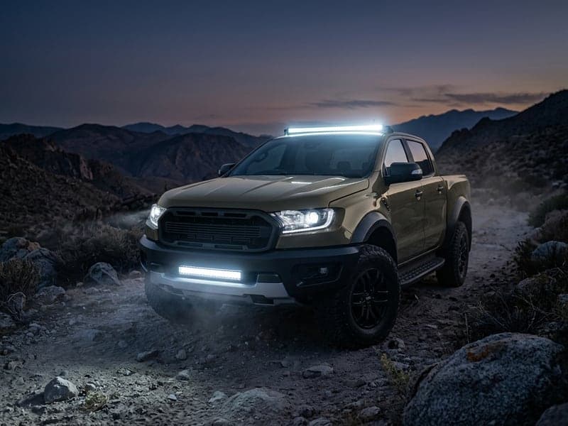 Rampe LED 4x4 allumée sur pick-up Toyota Tacoma en franchissement rocheux nocturne, faisceau longue portée puissant