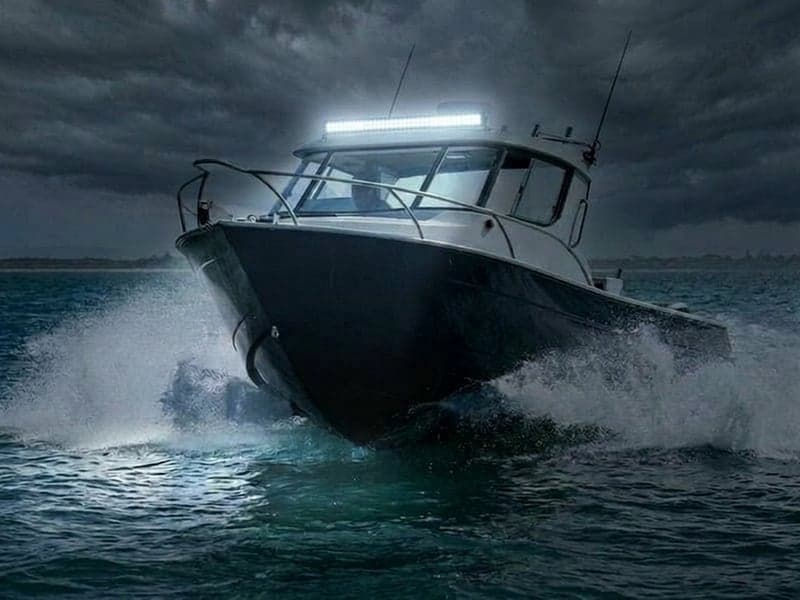 Barre LED étanche allumée sur bateau en navigation nocturne, faisceau puissant éclairant l'océan et les embruns