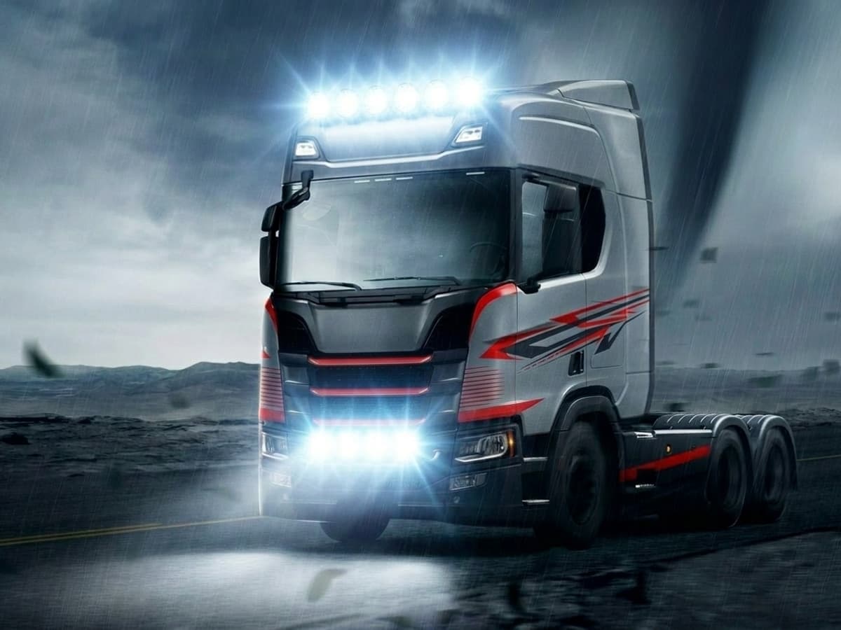 Phares LED 24V additionnels allumés sur camion poids lourd roulant de nuit sous la pluie, faisceau longue portée